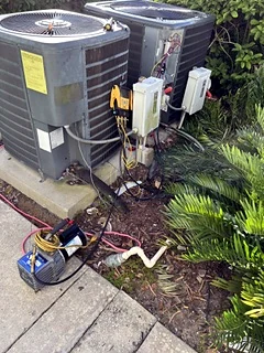 Outdoor condensers with a vacuum pump connected during a leak repair.