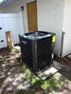 Newly installed outdoor condenser beside a gate.